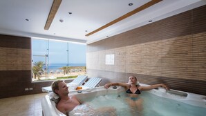 A modern indoor swimming pool with wooden paneling, a view of the beach, and lounge chairs. - Concorde Moreen Beach Resort & Spa (Marsa Alam)