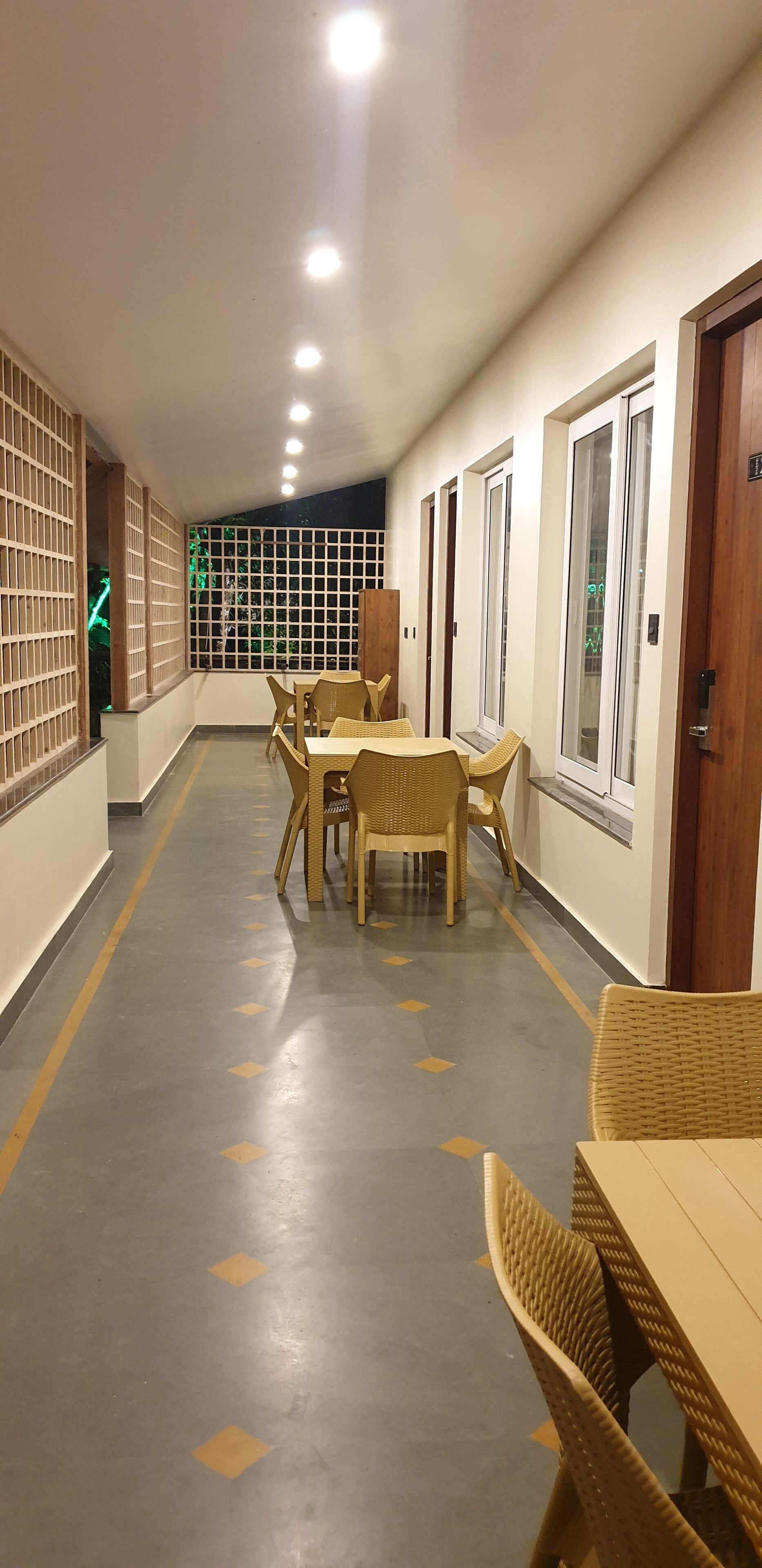 A corridor with a dining area featuring wicker furniture and a tiled floor with yellow diamond patterns.