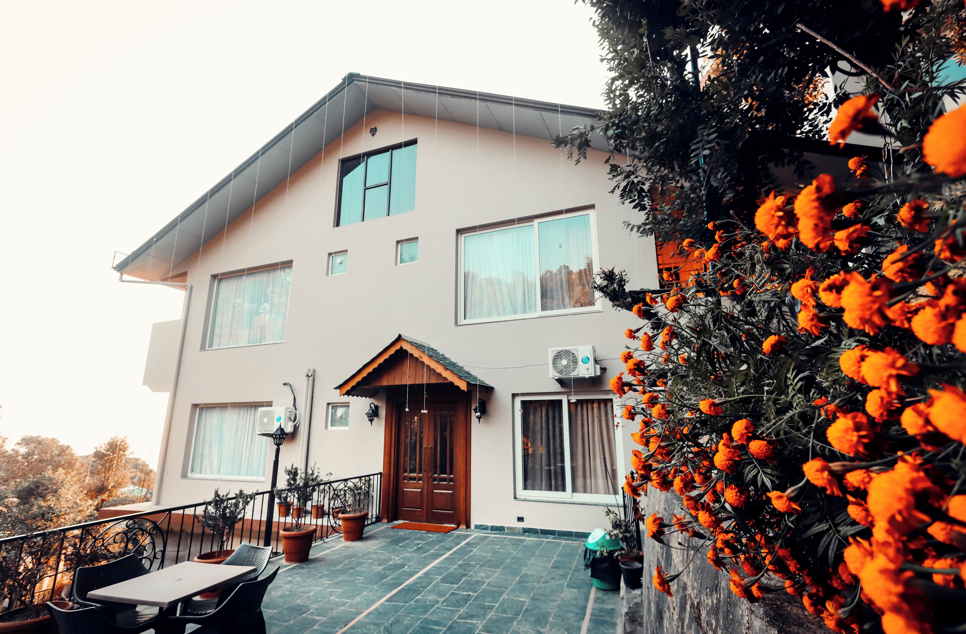 Ein zweistöckiges Haus mit Balkon, Blumentöpfen und einer Holztür.