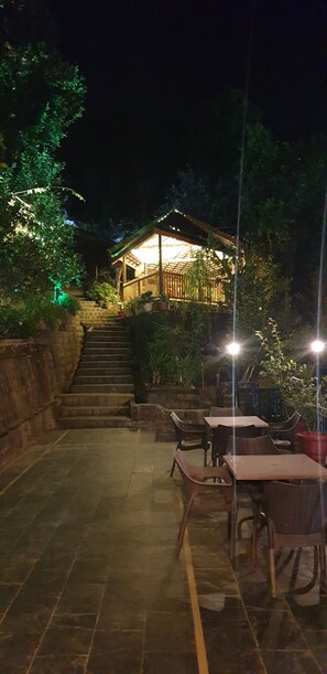 A patio area with outdoor seating and a staircase leading to a building. - Hotel Pong View (Dharamshala)