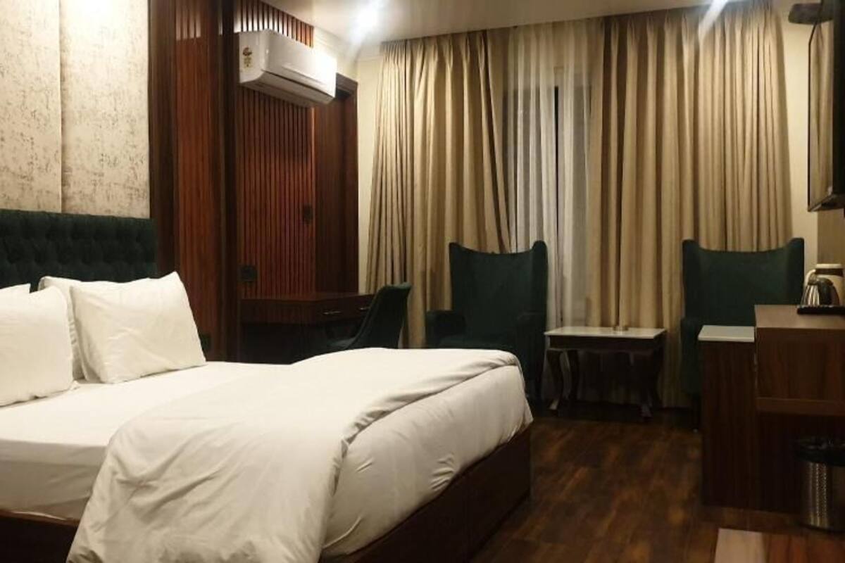 A hotel room with a bed, a desk, a chair, and a TV.
