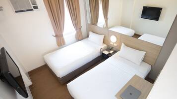 A hotel room with two beds, a TV, a desk with a laptop, and a mirror.