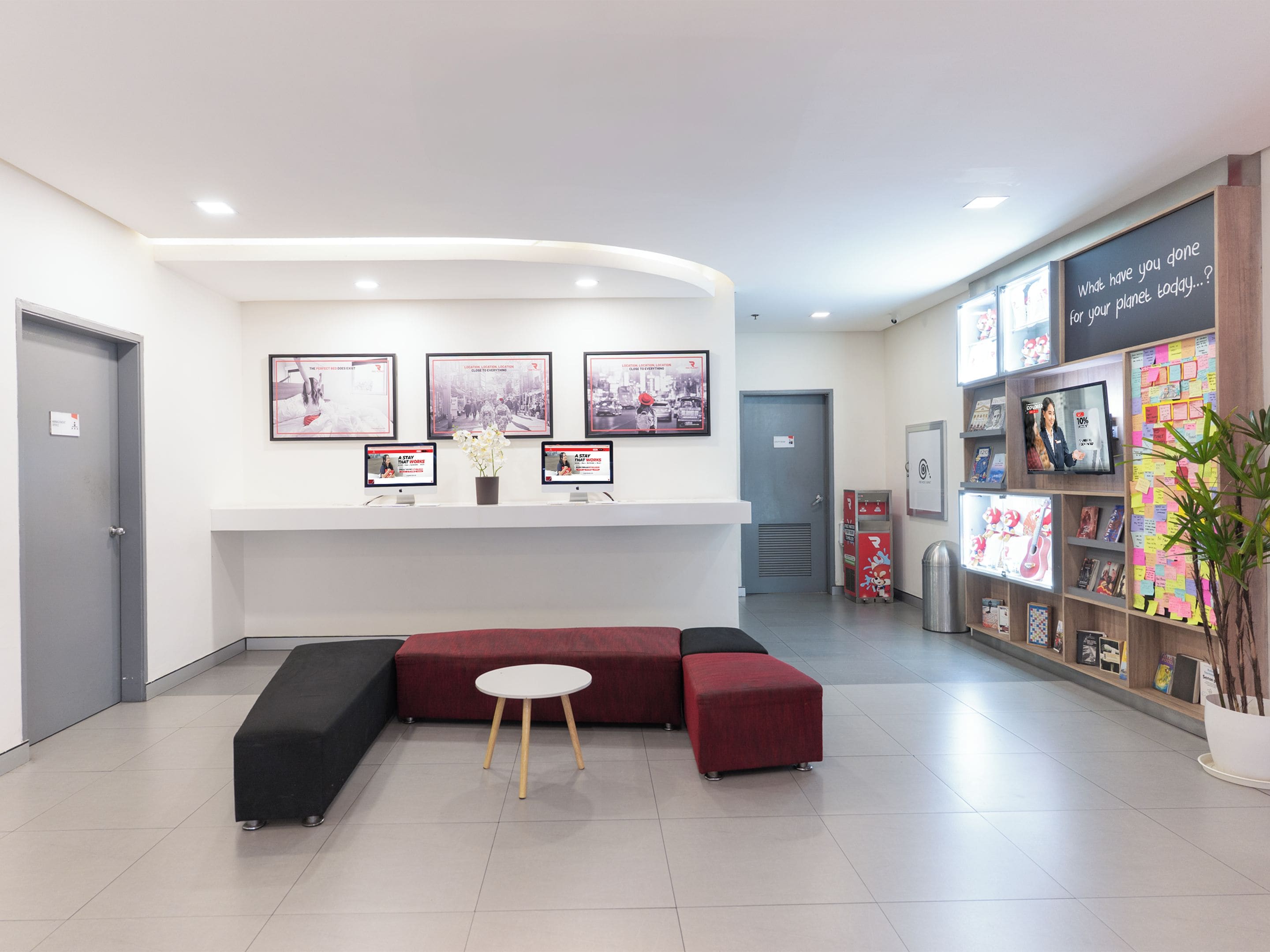 A reception area with a seating area, a wall-mounted TV, and a bulletin board with notes.