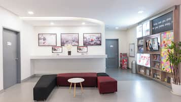 A reception area with a seating area, a wall-mounted TV, and a bulletin board with notes.