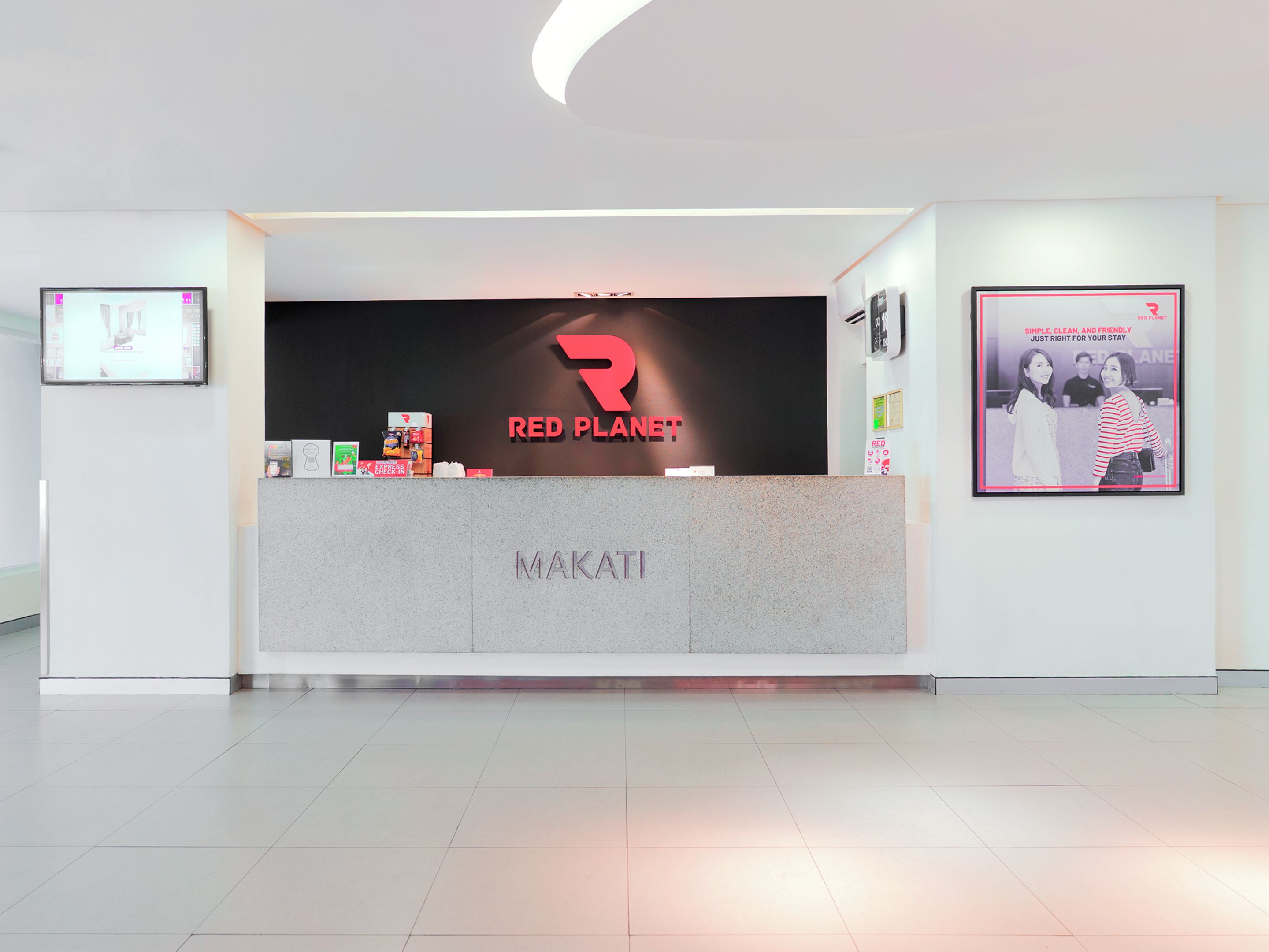 A reception desk with a Red Planet logo, a framed photo, and a sign for Makati.