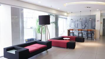 A modern lobby with seating, a cityscape mural, and a reception desk.