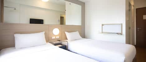 Habitación de hotel con dos camas individuales, un espejo grande, una mesita de noche, un televisor de pared y una puerta.
