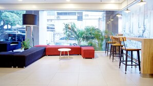 A modern lobby with a seating area, a reception desk, and large windows offering a view of the city. - Red Planet Makati Avenue Manila (Makati)