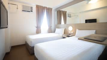 A hotel room with two beds, a desk with a laptop, a mirror, and a TV.