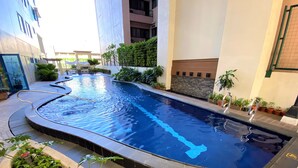 A swimming pool with a curved design, surrounded by potted plants and a tiled walkway. - One Pacific Place Serviced Residences (Makati)