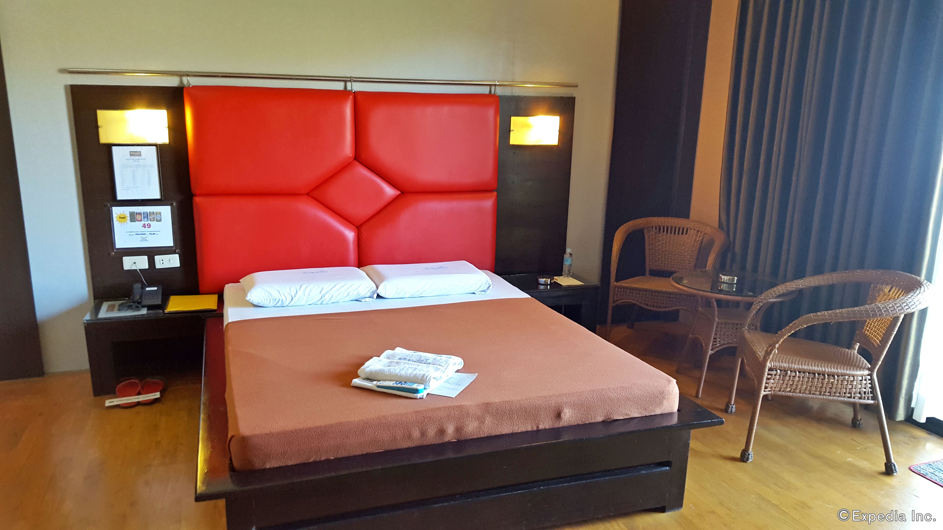Una habitación de hotel con una cama grande, una mesita de noche, una silla y una pequeña mesa.