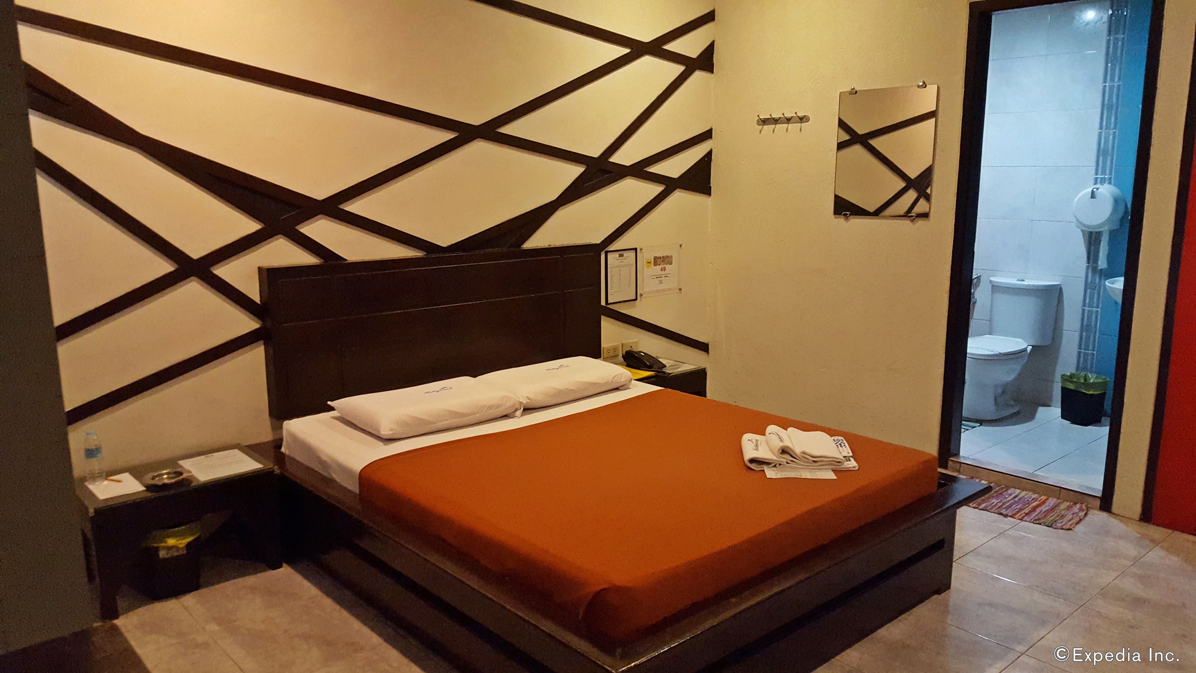 Una habitación de hotel moderna con una cama grande, una mesita de noche, un espejo y vistas al baño.