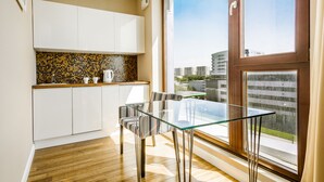 Une cuisine moderne avec des meubles blancs, un pare-feu en carreaux et un coin repas comprenant une table en verre et des chaises à rayures.