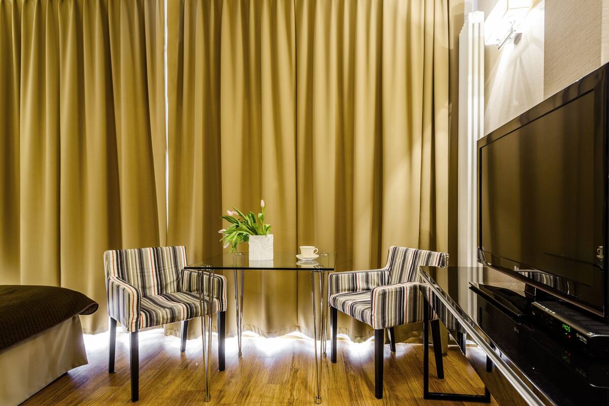 Un salon moderne avec une table en verre, des fauteuils à rayures, un canapé, un téléviseur à écran plat et une plante en pot.