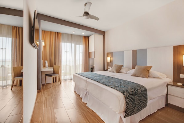 A modern hotel room with a large bed, a desk, and a chair. - Hotel Riu Festival (Palma de Mallorca)