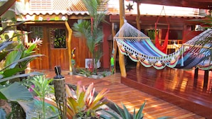 A wooden deck with a hammock, tropical plants, and a small garden area. - Physis Caribbean Bed & Breakfast (Cahuita)