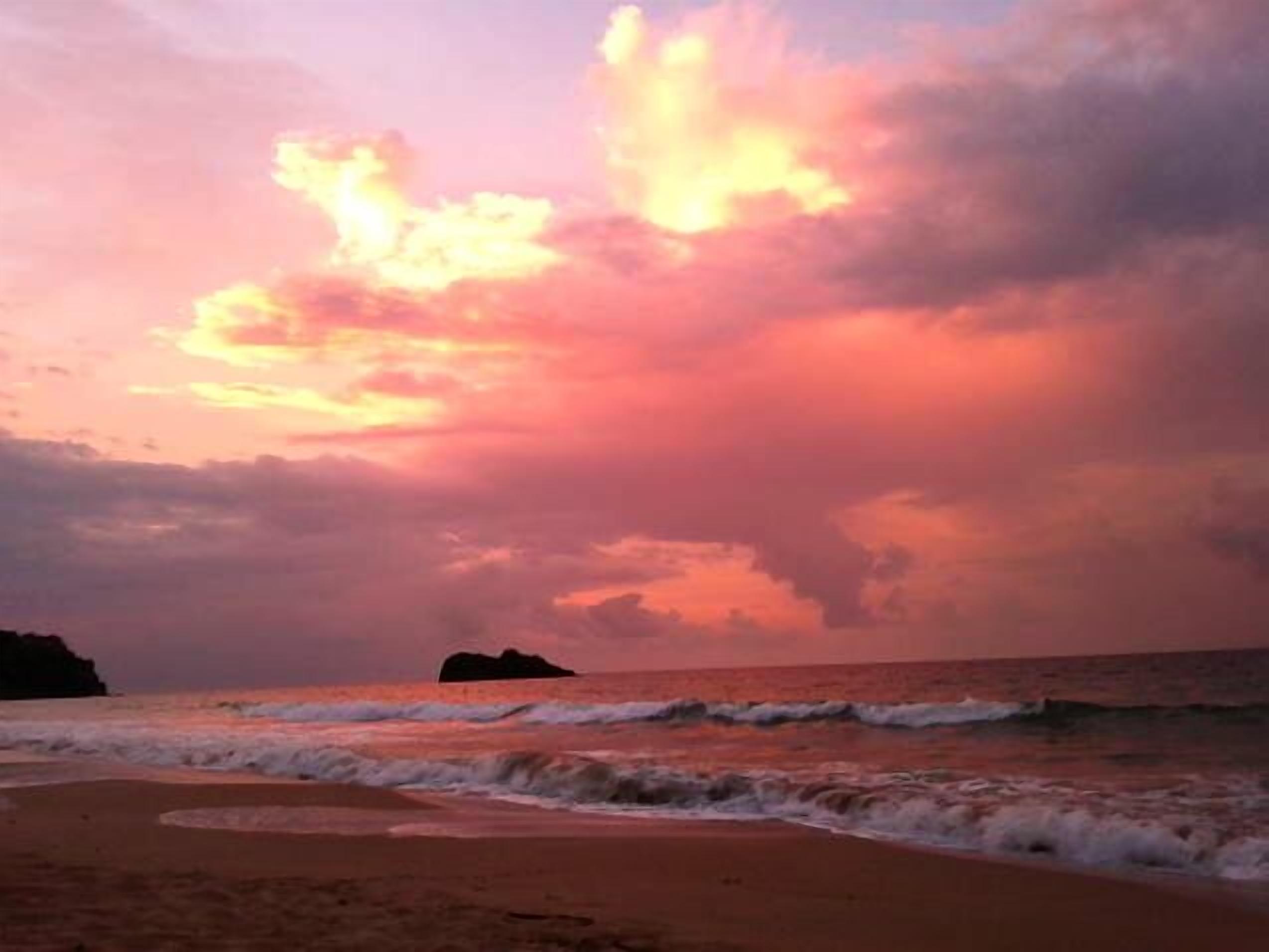 Une plage avec des vagues et un ciel au coucher du soleil.