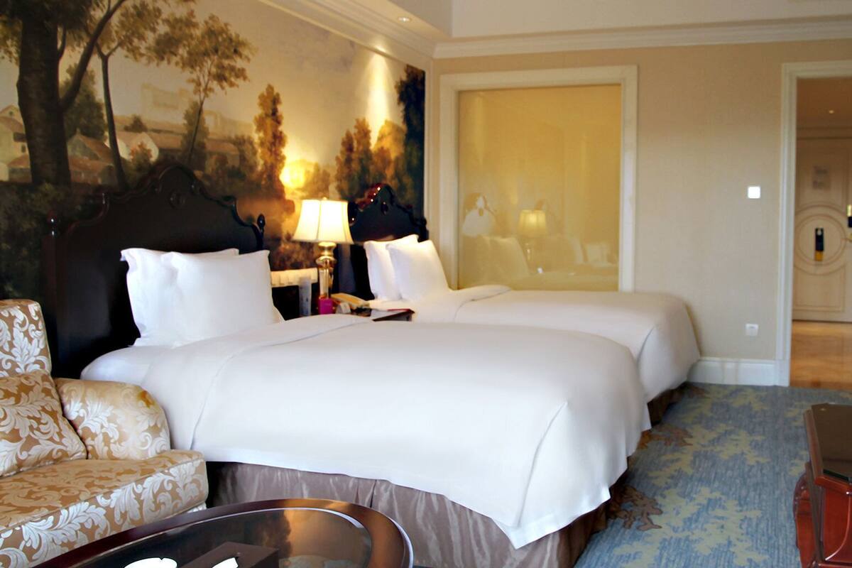 A hotel room with a large bed, two bedside tables, a TV, a desk, and a chair.