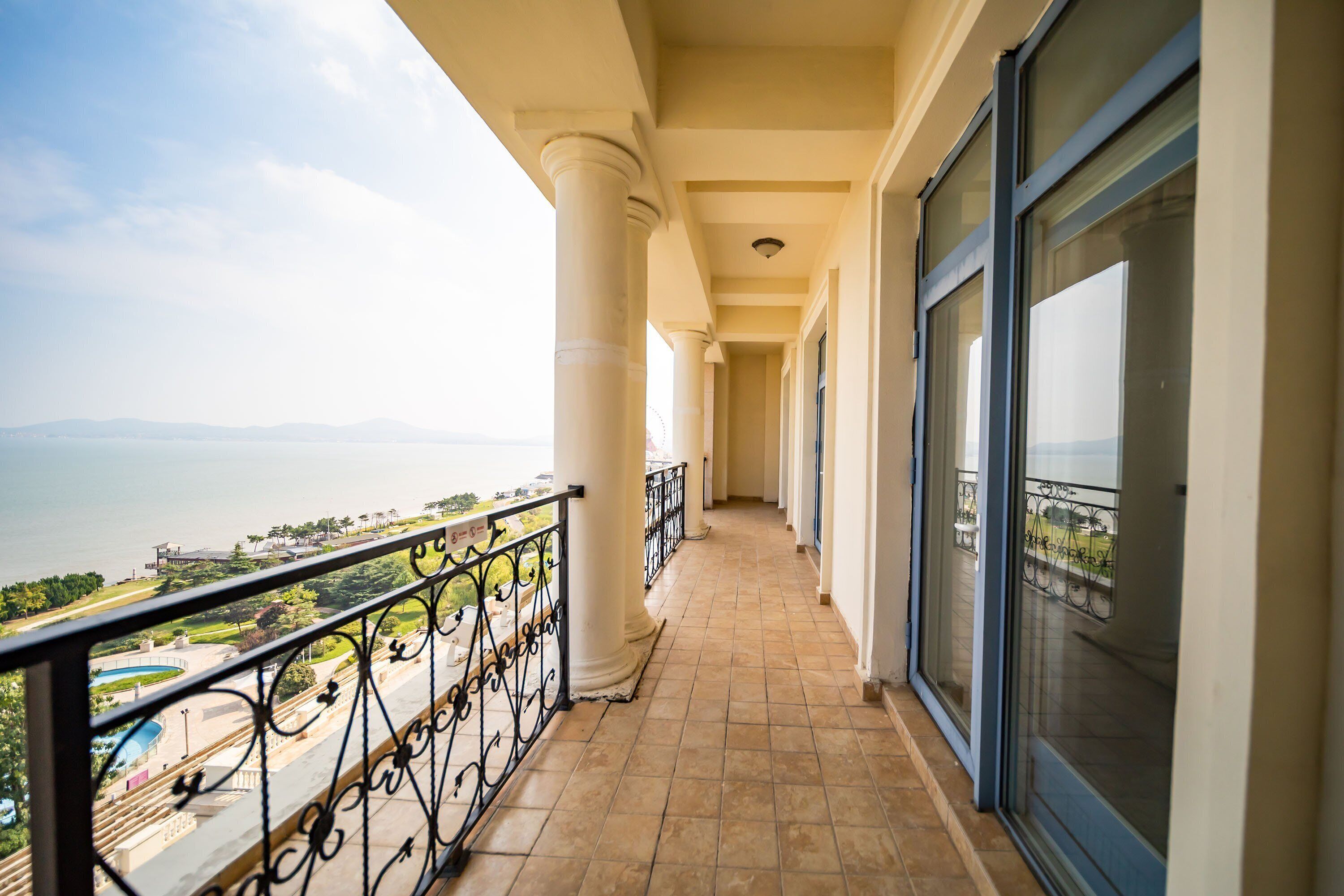 Un balcón con vista al mar, columnas y suelo de baldosas.