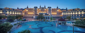 Een groot hotel met meerdere verdiepingen, een centrale binnenplaats en een zwembad.