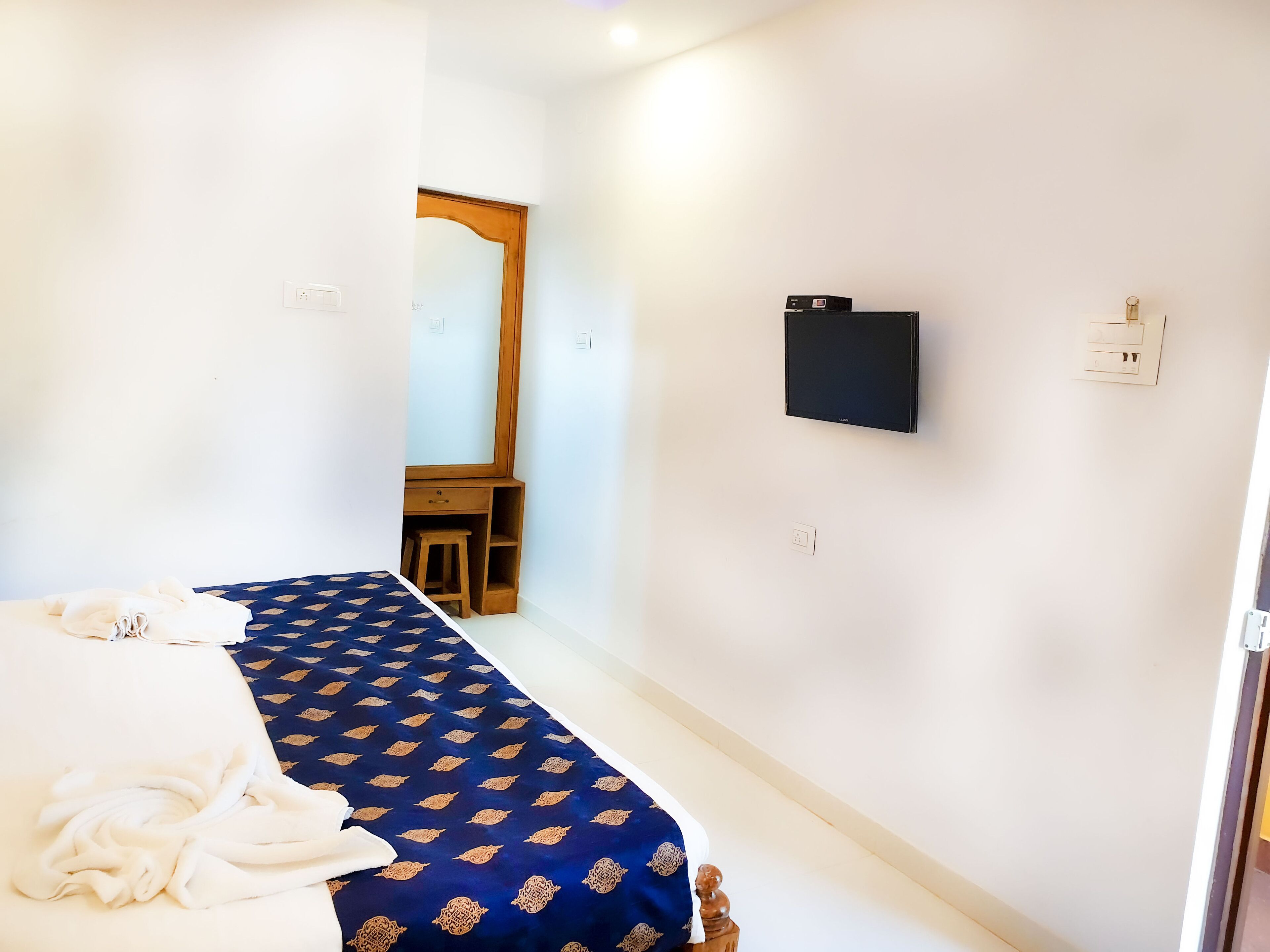 Une chambre à coucher avec un lit, un bureau, un miroir et une télévision.