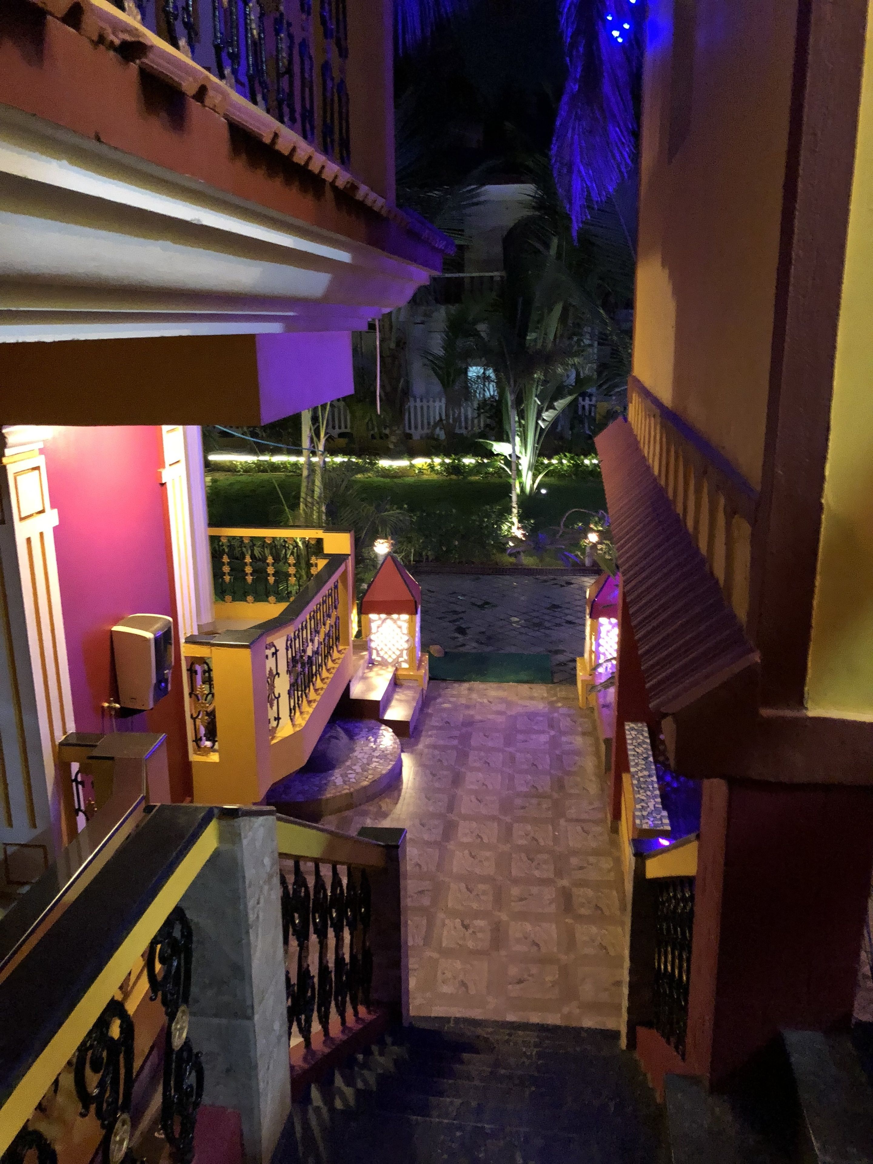 Una escalera conduce a un balcón con vistas a un jardín ajardinado de noche.