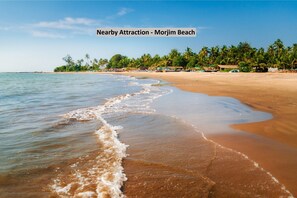 A beach with clear waters, palm trees, and beach huts. - Veronica Guest House (Calangute)