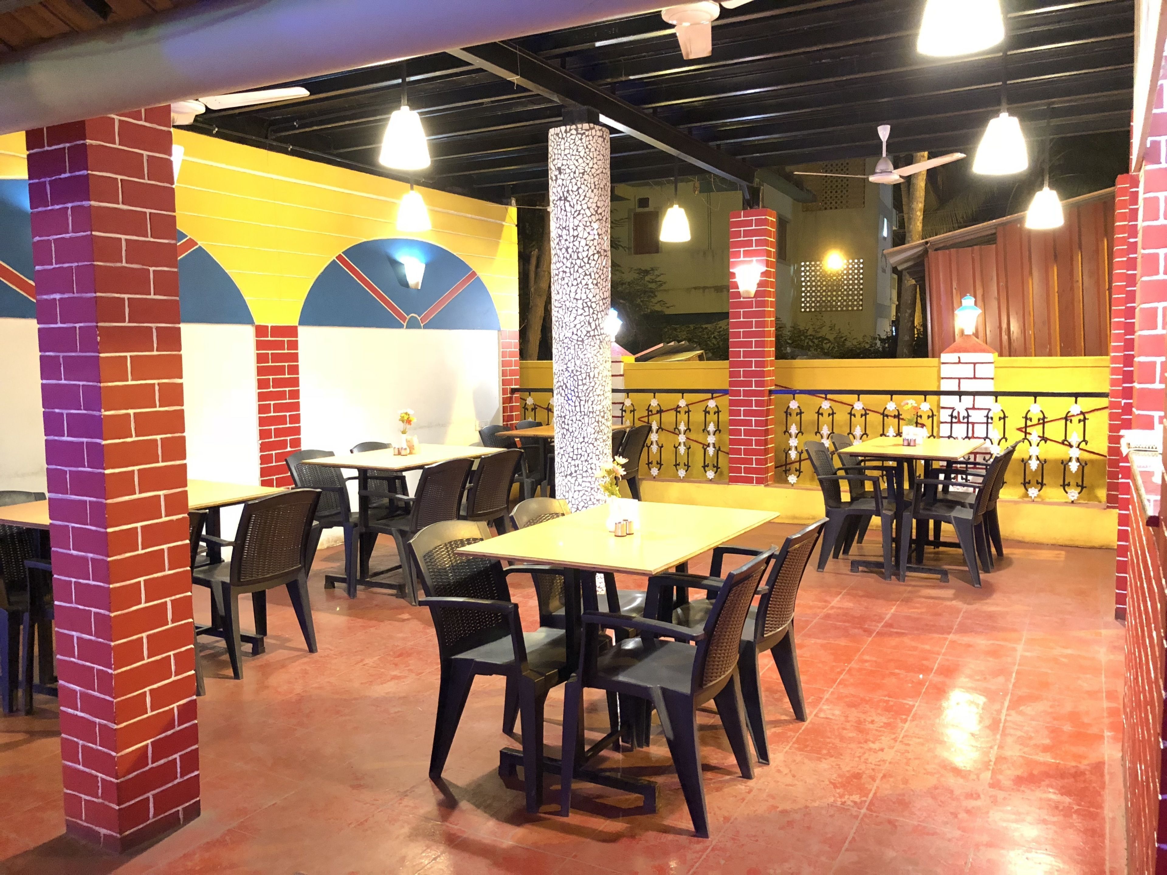 An indoor dining area with brick pillars, tables, and chairs.