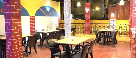 An indoor dining area with brick pillars, tables, and chairs.