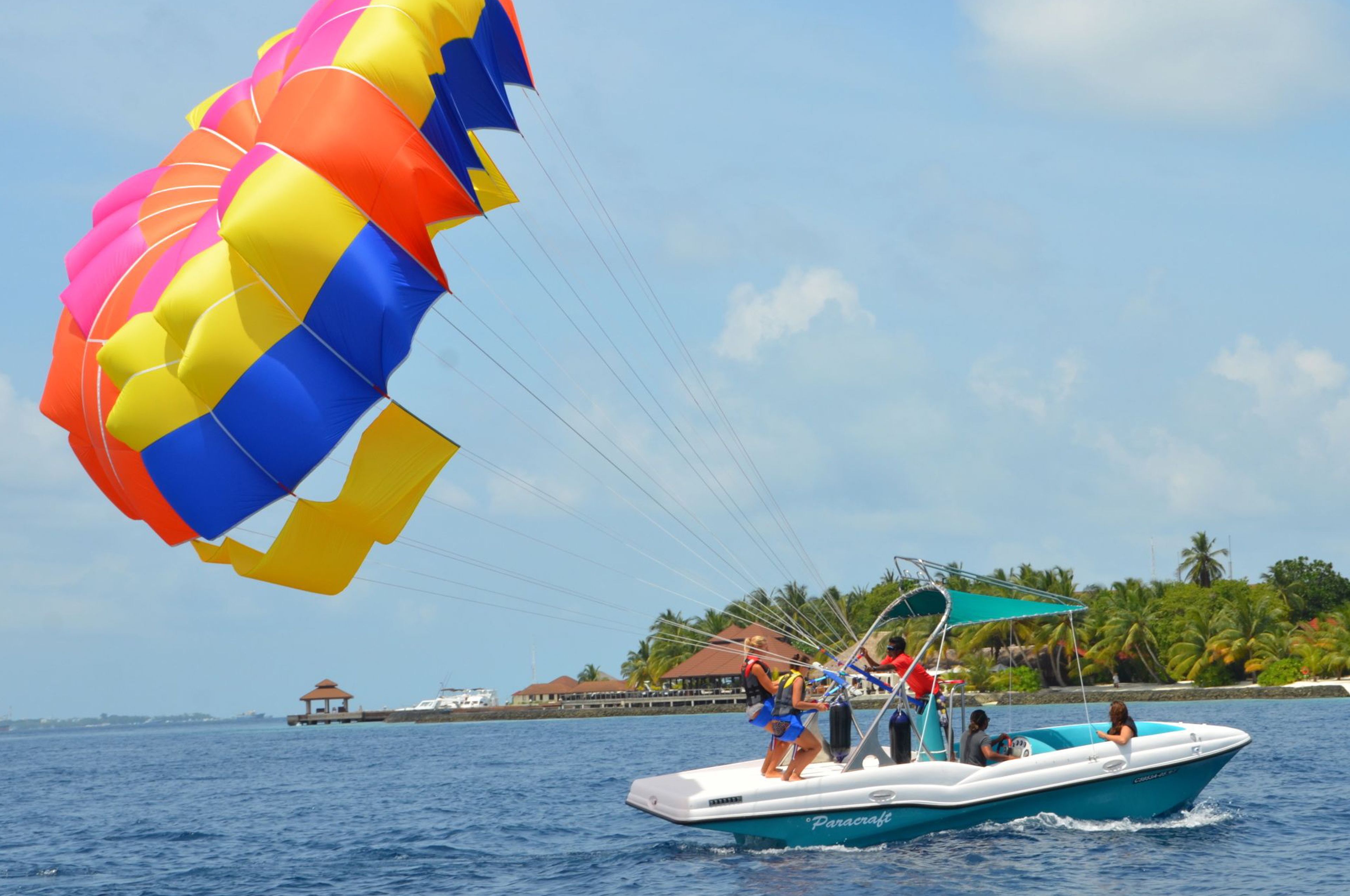 A parasailing boat with passengers and a colorful parachute.