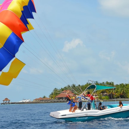 A parasailing boat with passengers and a colorful parachute.