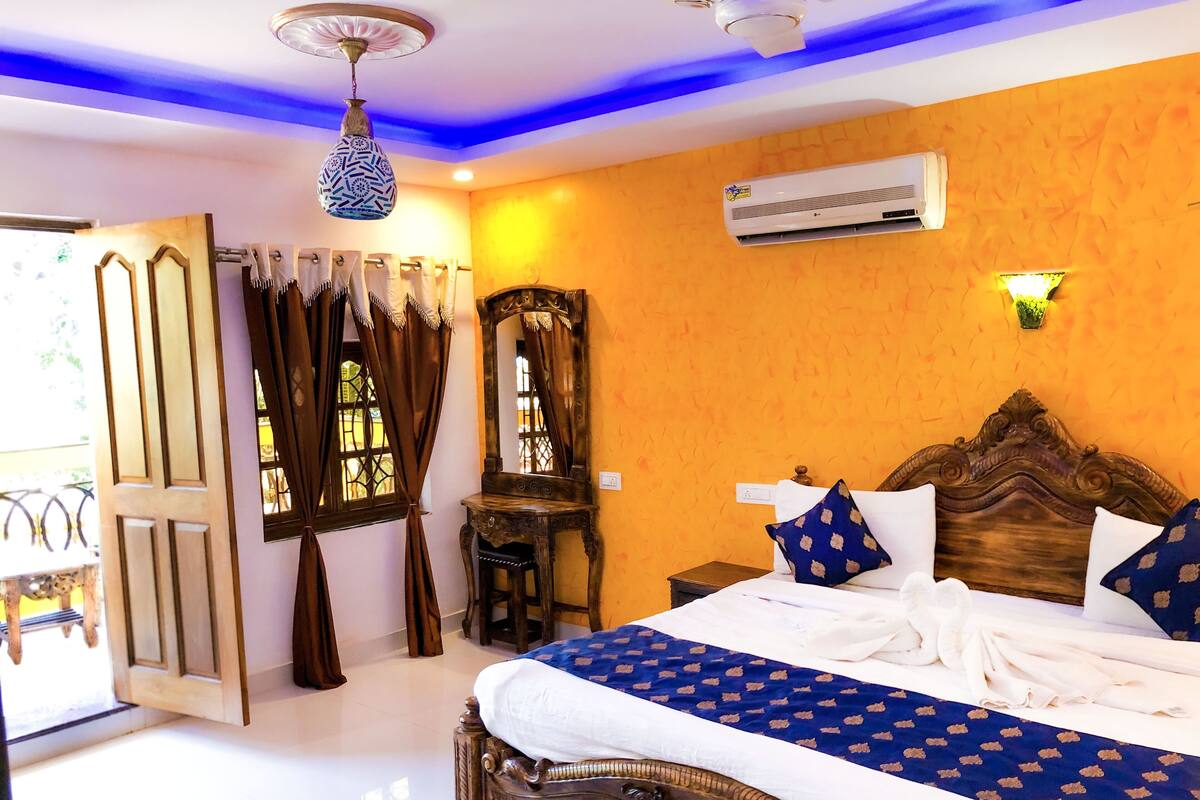 A bedroom with a wooden bed, a mirror, an air conditioner, and a window with curtains.