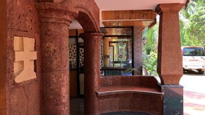 A stone archway leading to a reception area with a glass door, a wooden ceiling, and a vehicle parked outside. - Veronica Guest House (Calangute)