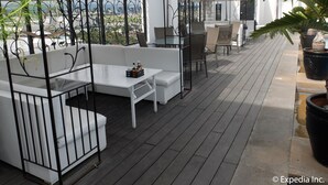 Een terras op het dak met witte meubels, waaronder een bank en een tafel, onder witte zonnedoeken.