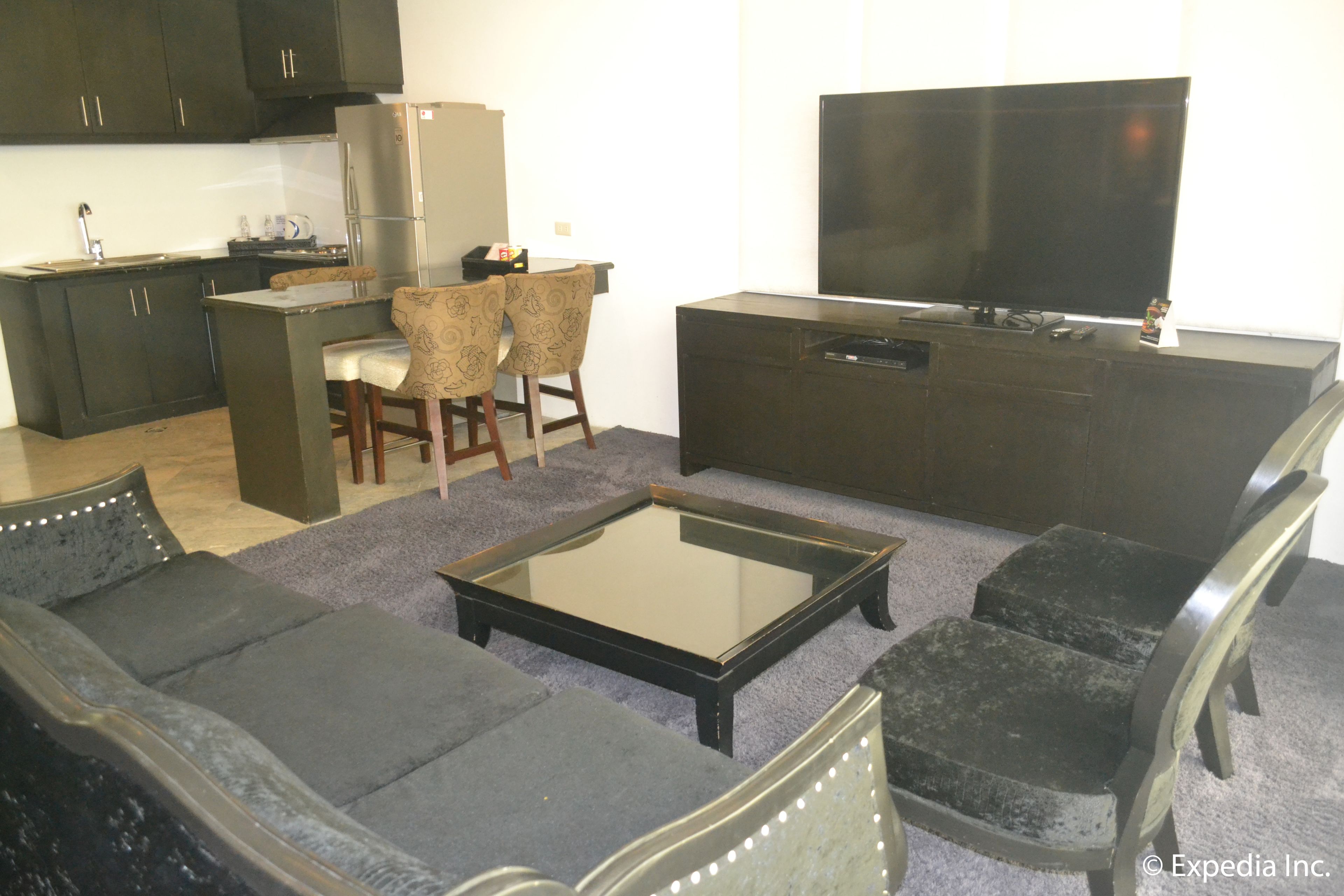 Un salon moderne comprenant un canapé, des fauteuils, une table basse et un téléviseur à écran plat.