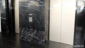 Een moderne lift met een marmeren wand en bedieningspaneel.