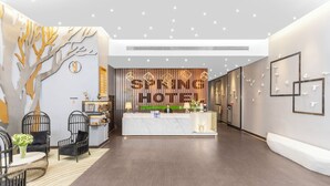 A modern hotel reception area with a central counter, seating area, and decorative wall art. - Spring Time Hotel (Guangzhou)