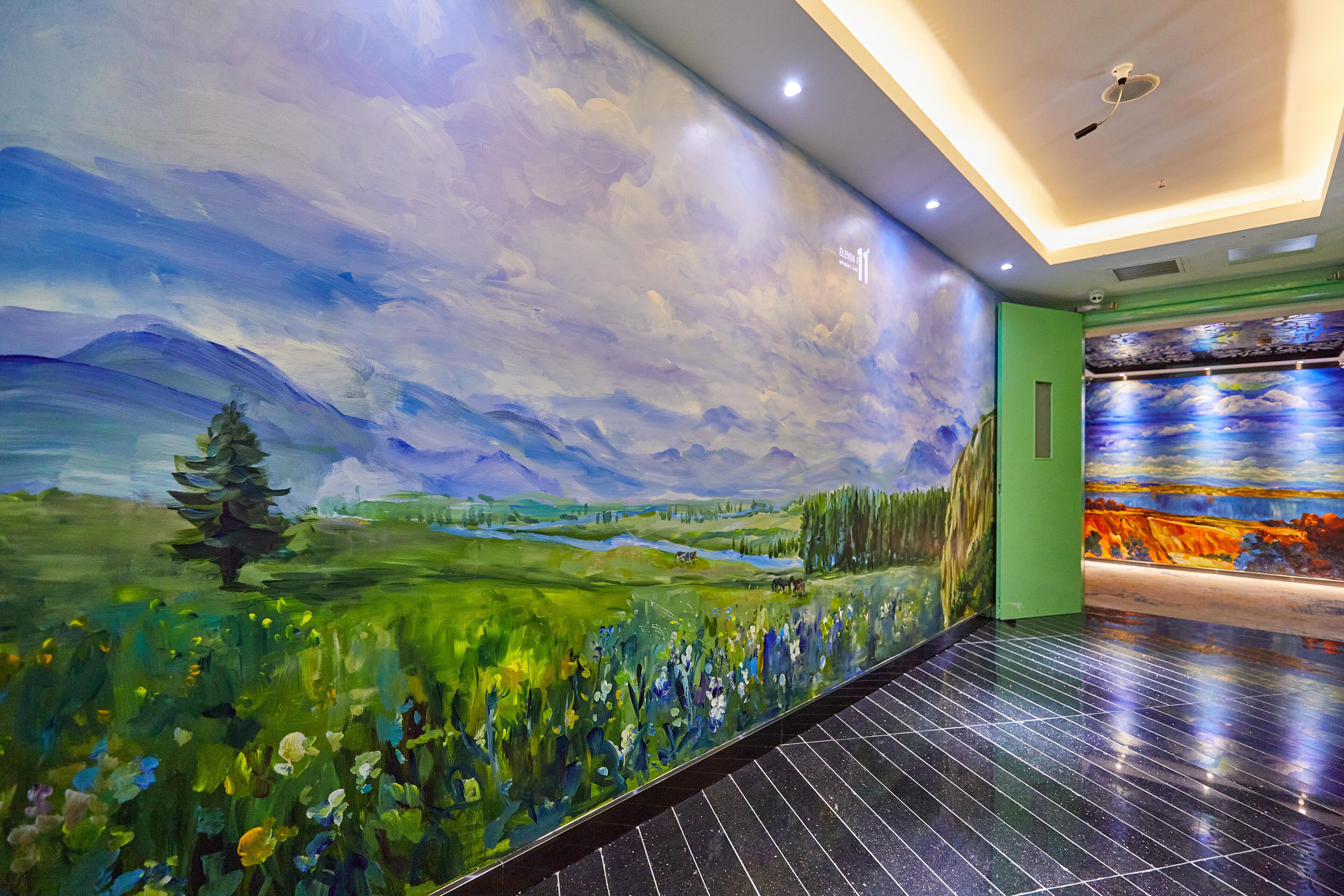 Un pasillo con un mural de un paisaje y una puerta verde.