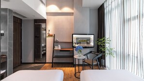 A modern hotel room with a bed, a desk, a TV, and a view of the city. - Spring Time Hotel (Guangzhou)