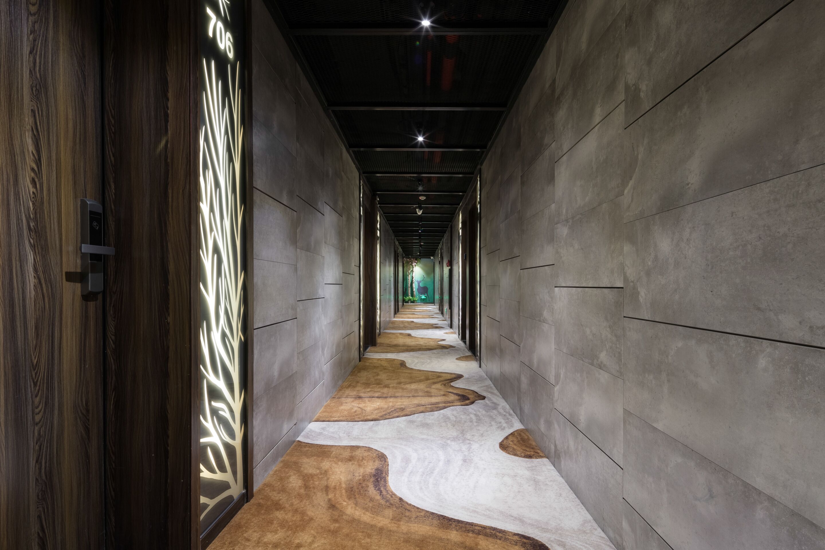 A corridor with a unique floor design, a modern light fixture, and a door with a number.
