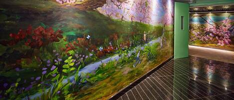 A corridor with a large floral mural on the wall and a green door.