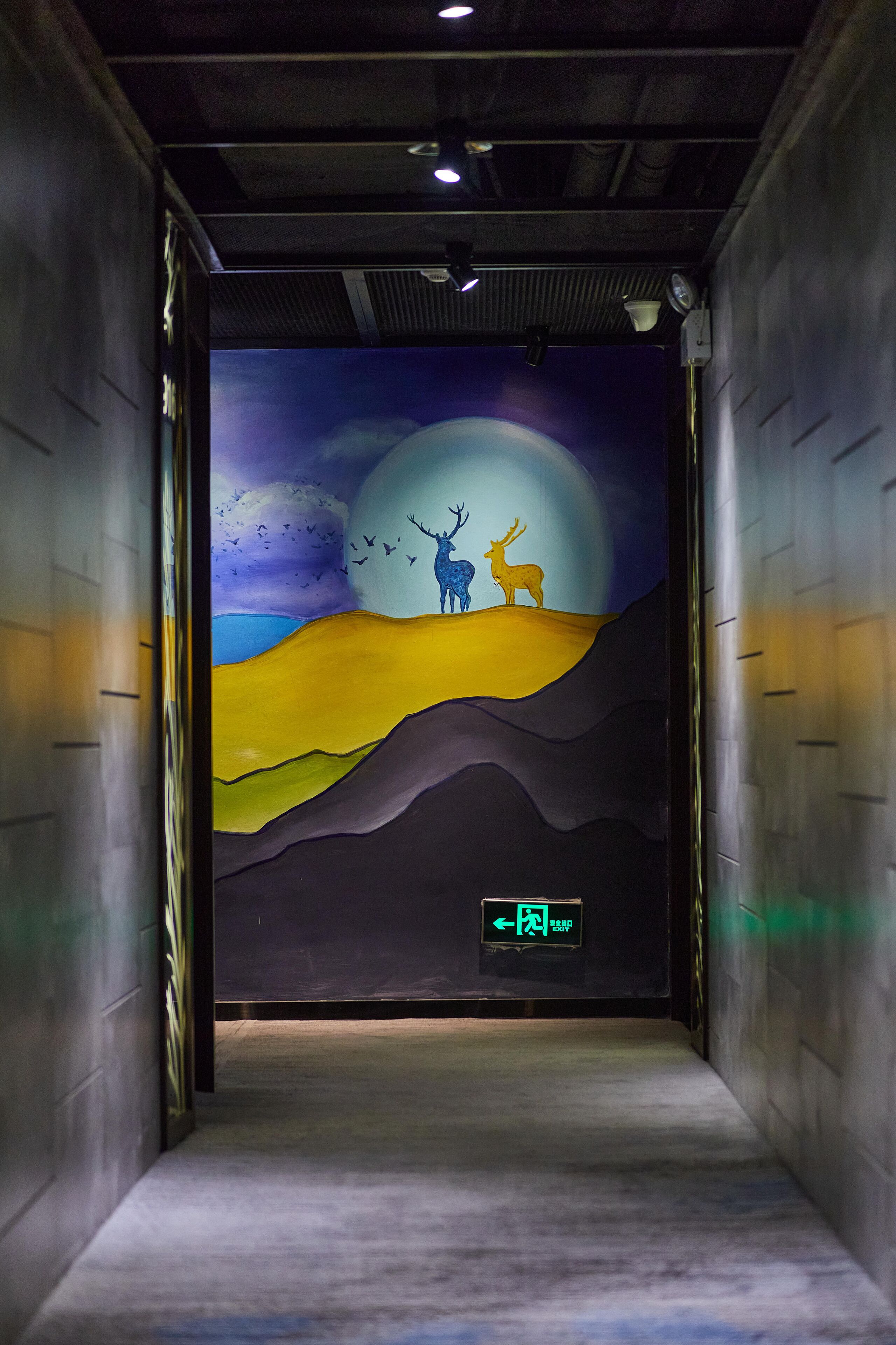 A hallway with a mural of deer on a hill under a moon.