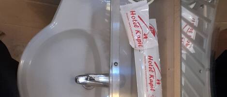 A toilet with a bidet attachment, a glass partition, and two packages labeled 'Hotel Kapie'.