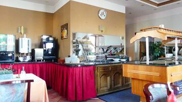 A restaurant with a red tablecloth, a coffee machine, and a clock on the wall.