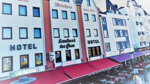 A row of traditional European hotels with "Hotel" signs, a red awning, and a visible outdoor seating area. - Kunibert der Fiese (Cologne)