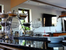 Montaje de bufé con varias estaciones de servicio, incluyendo fuentes de comida y un dispensador de bebidas.