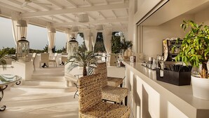 A covered outdoor seating area with wicker chairs, a bar counter, and hanging lanterns. - Tenuta del Poggio Antico (Forio)
