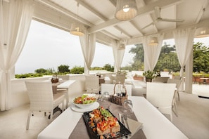A restaurant with white furniture and a view of greenery. - Tenuta del Poggio Antico (Forio)