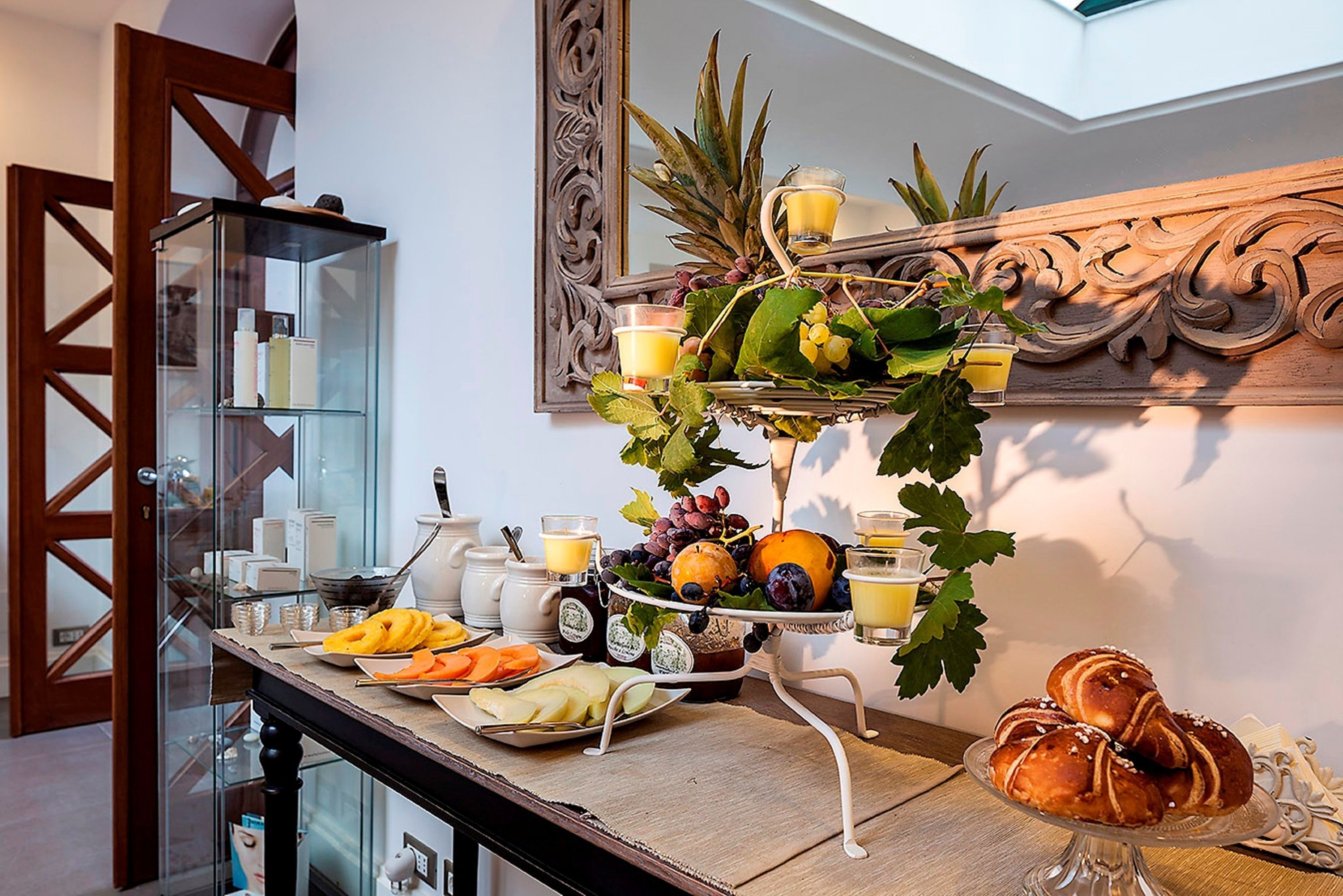 A breakfast buffet with fruits, pastries, and beverages on a wooden table.