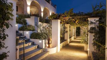 Una scalinata esterna ben illuminata con pareti e archi bianchi, che conduce all'ingresso di un edificio.